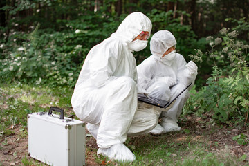 Ecological problem. Pollution. Examine soil. Scientist working in forest in protective mask and suit taking water and soil samples. Chemist makes an analysis of the environment for radiation. 