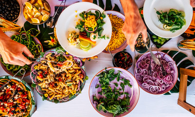 People together during party event celebration taking mixed healthy food from a table - fresh chef meal ingredients on a table- concept of catering and restaurant