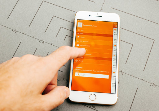 PARIS, FRANCE - SEP 26, 2016: Male hand holding New Apple iPhone 7 Plus after unboxing and testing by installing the app application software ING online banking money trasfer