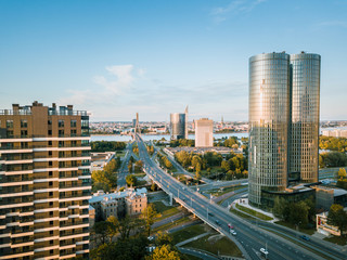 Fototapeta premium Panoramic, aerial view over Riga city. Modern buildings, roads, and other infrastructure. Cable bridge leading to iconic old town panorama in vivid sunset colors. 