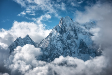 Naklejki  Góra Manaslu z ośnieżonym szczytem w chmurach w słoneczny jasny dzień w Nepalu. Krajobraz z wysokimi śniegiem pokrytymi skałami i błękitnym zachmurzonym niebem. Piękna natura. Bajkowa sceneria. Widok z lotu ptaka na Himalaje