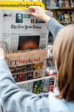 STRASBOURG, FRANCE - OCT 28, 2017: Woman buying The New York Times newspaper  business at press kiosk featuring article about Nigerian Girls