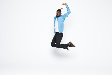 Fototapeta na wymiar Full length portrait of cheerful handsome joyful afro man wearing casual denim jeans clothing jumping up, isolated on gray background