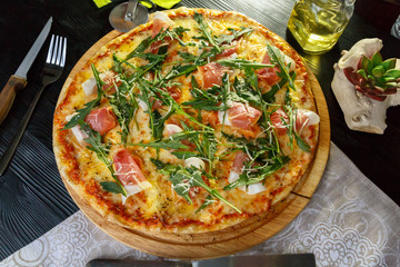 Pizza with bacon, cheese and herbs on a black wooden background