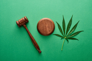 Fototapeta na wymiar top view of green marijuana leaf with wooden gavel on green background