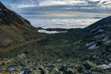 Fototapeta premium High mountains. View of the valley with the lake, many beautiful clouds below and above.