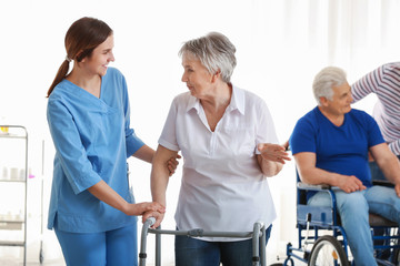 Young caregiver looking after disabled senior woman in nursing home