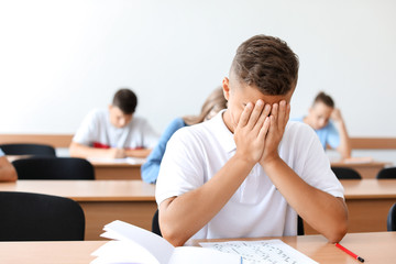 Unhappy boy passing school test in classroom