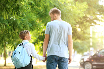 Little boy going to school with his father