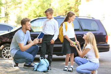 Parents getting their children ready for school outdoors