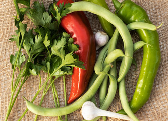 Dill, red pepper, bean pods, garlic, green pepper on burlap, top view