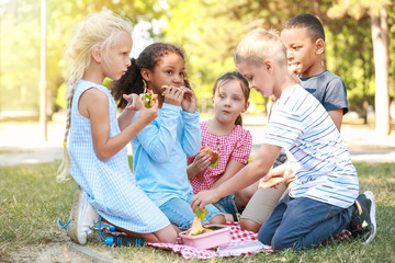 Cute little children having lunch in park