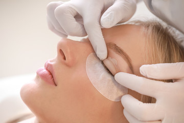 Young woman undergoing procedure of eyelashes lamination in beauty salon, closeup