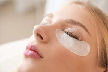 Young woman undergoing procedure of eyelashes lamination in beauty salon, closeup