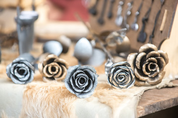Five metal roses of silver and gold color on the table at the seasonal fair of masters.