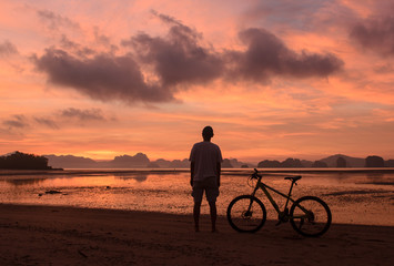 Silhouette of a man riding bicycle on beach