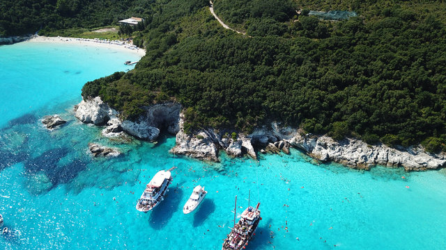 Aerial drone photo of tropical paradise turquoise beach of Voutoumi with sail boats docked in island of Anti paxos, Ionian, Greece