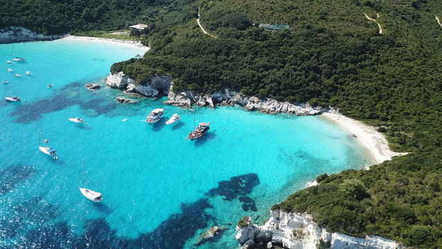 Aerial drone photo of tropical paradise turquoise beach of Voutoumi with sail boats docked in island of Antipaxos, Ionian, Greece