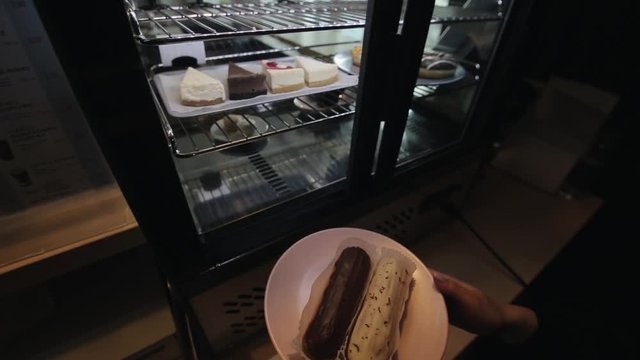 A female hand taking a plate with eclairs out of the fridge