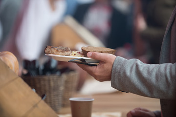 Men's hands take a plastic plate of food. The concept of helping the homeless and the needy.