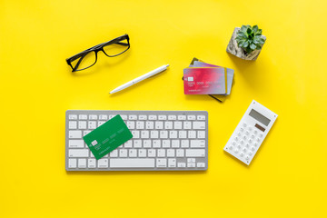 Banker work place with credit cards, keyboard and calculator on yellow background top view