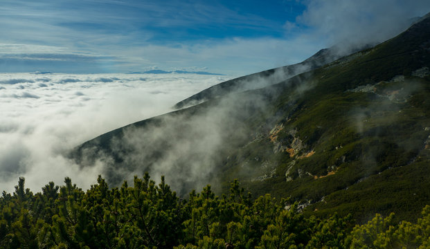 Above the clouds. High mountains, covered by a veil of clouds.