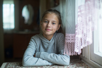 Portrait of a teenage cute girl sitting at the table.