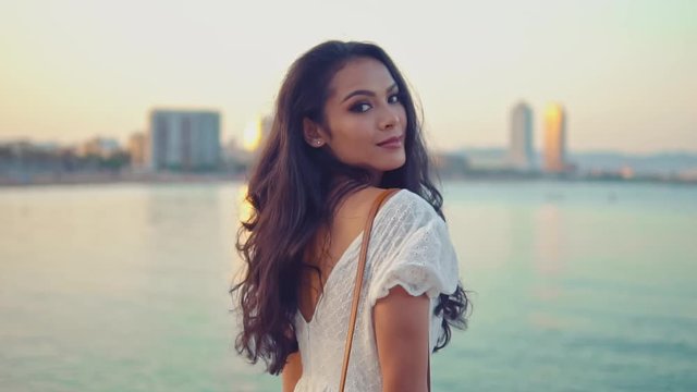 Beautiful girl in the white dress walking along the sea promenade. Elegance and tenderness concept