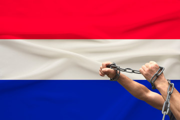 muscular male hands wrapped in a thick iron czar against the background of the state flag, the concept of political struggle, crime, cruelty, imprisonment, violation of human freedom
