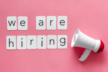 We are hiring announcement with megaphone and text on pink background top view