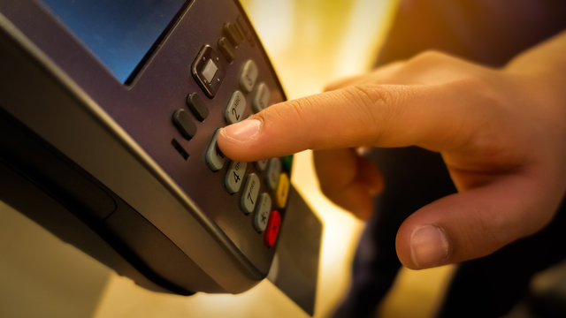 Close up of a hand entering the credit card pin code on a card reader machine.