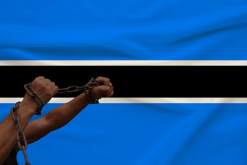 muscular male hands wrapped in a thick iron czar against the background of the state flag, the concept of political struggle, crime, cruelty, imprisonment, violation of human freedom