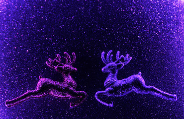 Christmas glitter deer on violet sparkling background. Neon light. Christmas concept.
