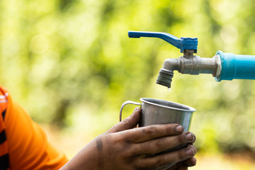 Water from tab pouring in hand on nature background, Concept for save water,conservative environment