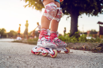 Close up on child's legs wearing roller blades skates learning to ride on the asphalt in the school...