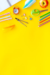 Creative mess on student's desk on yellow background top view mockup