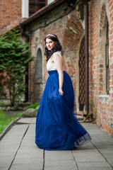 Portrait of Sensual Young Brunette Lady Dancing in Long Blue Dress. Wearing Tiara.