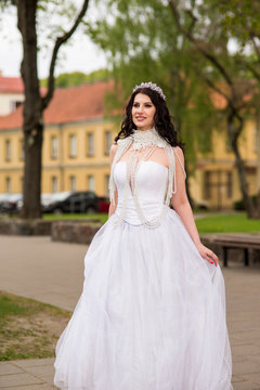 Young Caucasian Bride With Crown and Beads Necklace. posing In Park Outdoors in The City