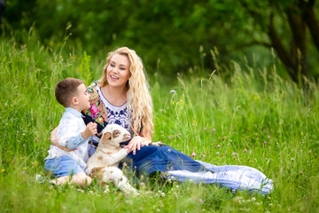 Smiling Mother with Her Little Happy Son and Cub of Newborn Lamb Posing Outdoors on Nature Background.