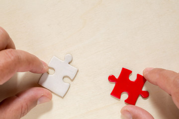 hand connecting two puzzle pieces on table background