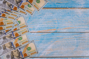 One hundred dollar bills on blue wooden background.