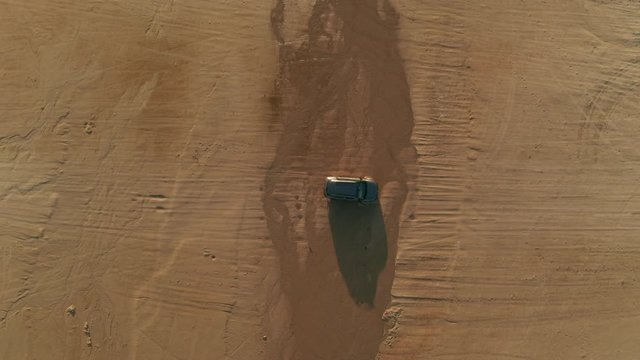 Car driving on the beach through little water