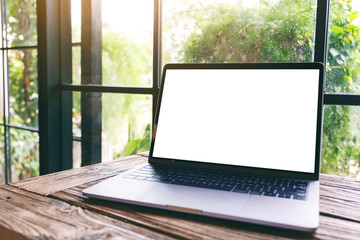 Mockup image of laptop computer with blank white desktop screen on wooden table