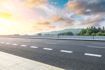 Fototapeta premium Country road and green woods nature landscape at sunset