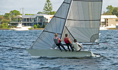 High school teens Sailing small sailboat with a Strong Wind on a lake. Lake Macquarie, Australia.