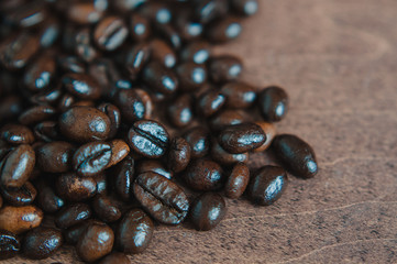 Freshly roasted scattered dark coffee beans, with mood filter, close up