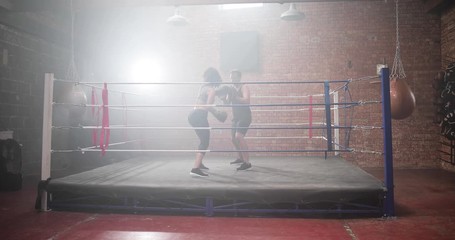 Female boxer with trainer using focus pads