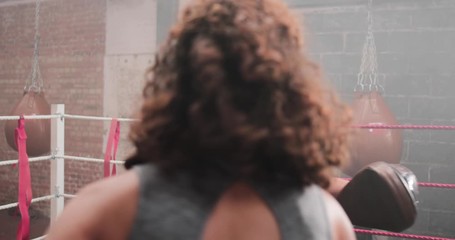 Female boxer with trainer using focus pads