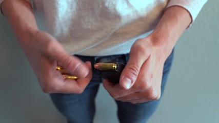 Women completely emptying bullets from handgun magazine and reloading it for safety