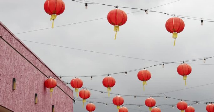 Multiple Chinese lantern lights hanging below a cloudy day. Tilt up sky view in 4k slowmotion.mov